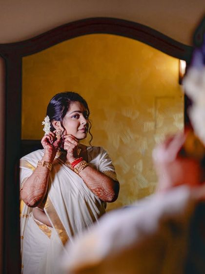 A South Indian bride getting ready, captured in a mirror's reflection. This shot focuses on the traditional details and the bride's calm demeanor.