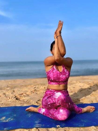 Gomukhasana, or Cow Face Pose, provides a deep stretch for the hips and shoulders. Here, I am practicing the arm variation, Garudasana arms, to release tension in the upper back while seated on the beach.