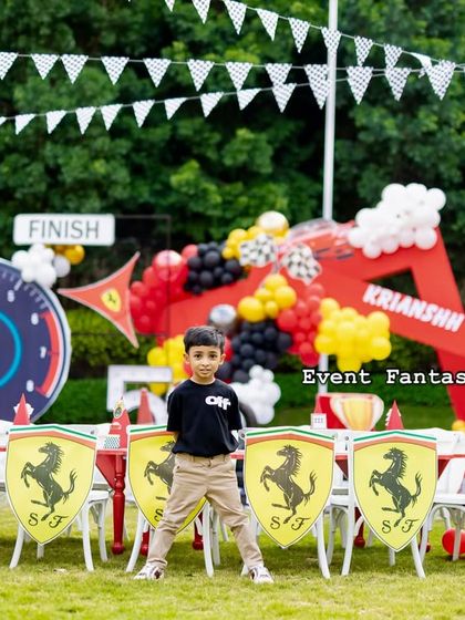 The birthday boy posing proudly in front of the custom dining area at his Ferrari party.
