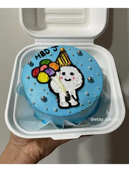A festive birthday bento cake with a cartoon character holding balloons, perfect for a cheerful celebration.