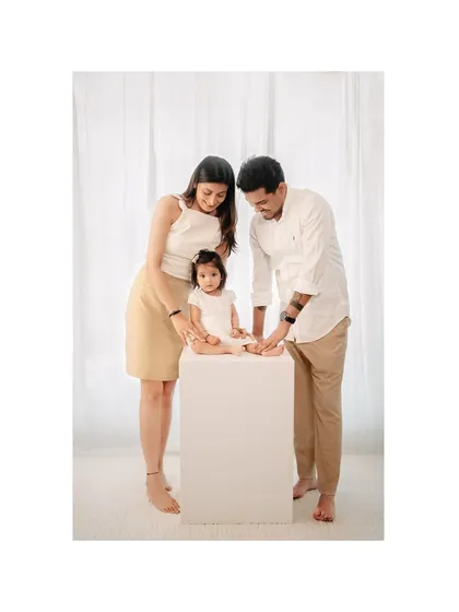 A classic family portrait with a modern, minimalist feel. The parents' loving attention is all on their daughter, creating a timeless and heartfelt image.
