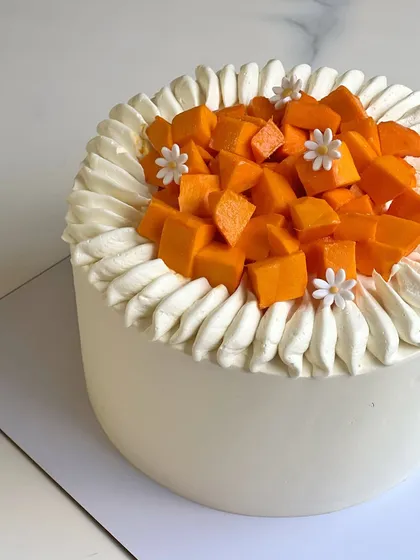 Another beautiful mango cake, this one featuring a simple white frosting and a pile of fresh, juicy mango chunks in the center. A classic summer treat.
