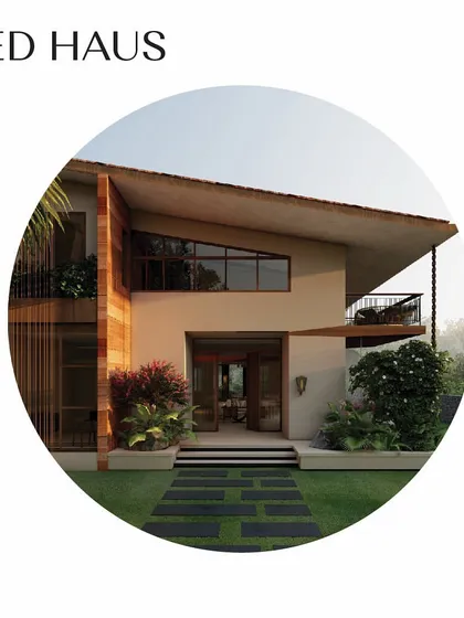 The entryway to the 'Red Haus' features a striking pitched roof and large openings that frame the lush surroundings. The combination of brick, terracotta, and welcoming trees makes this villa feel like a warm and inviting home.