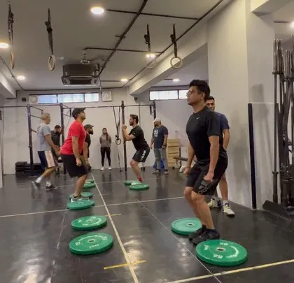 Athletes work on their squat mechanics by standing on plates, a drill designed to improve balance and reinforce proper foot pressure during a lift.