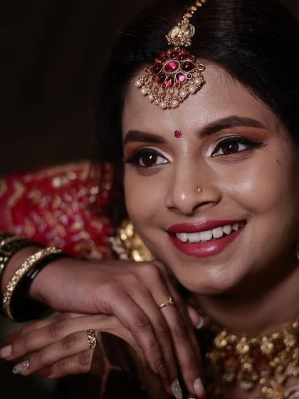 A beautifully lit portrait of bride Madhurya. The soft lighting enhances the glow of her skin and the richness of her red bridal attire.