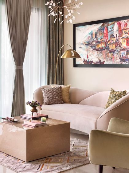 A different angle of the modern-traditional living room, showing the elegant curved sofa and the vibrant ghat painting.
