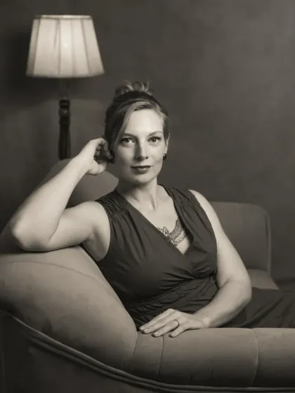 A black and white version of a portrait of Sonia on a chaise lounge. The monochrome treatment enhances the classic, cinematic feel of the image, focusing on her expression and the elegant lines of the pose.