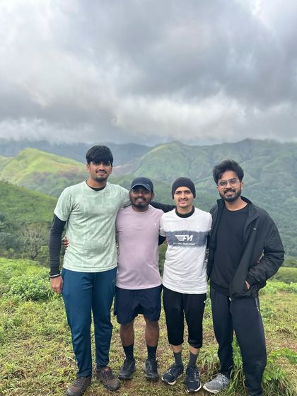 A group of friends posing together on the trail, with the beautiful Kudremukha hills as their backdrop.
