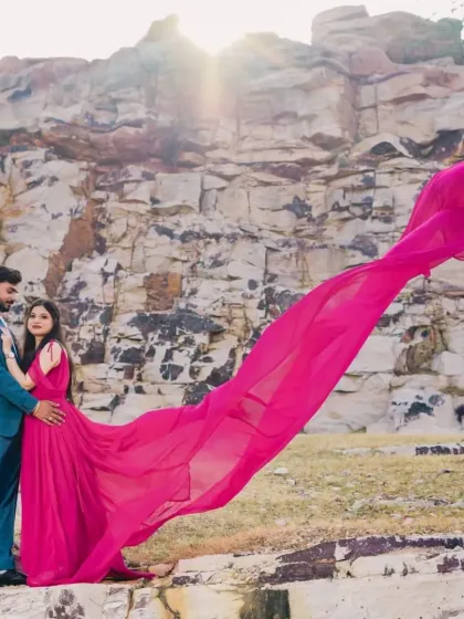 A similar shot showing the couple against a rocky cliffside. The long pink trail provides a beautiful splash of color and sense of scale.