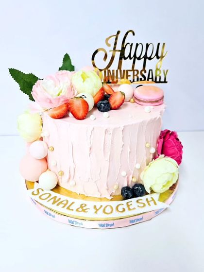 An anniversary cake that’s both delicious and beautiful. This single-tier cake in our popular Lotus Biscoff Strawberry flavor is finished with a rustic pink frosting and decorated with fresh flowers, fruits, and a macaron.