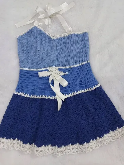 This is the Aviva Dress, a beautiful piece featuring multiple textures and a gradient of blue hues. The design includes a ribbed bodice, a lace-like middle panel, and a textured skirt.