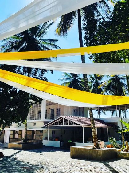 This shot captures the breezy, relaxed feel of an outdoor haldi ceremony. The overhead fabric drapes provide shade while adding a splash of color to the venue.