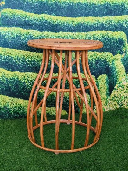 A beautifully crafted rattan side table with an hourglass shape. The intricate design, featuring gracefully curved rattan poles, makes it a decorative and functional accent piece for any living space.