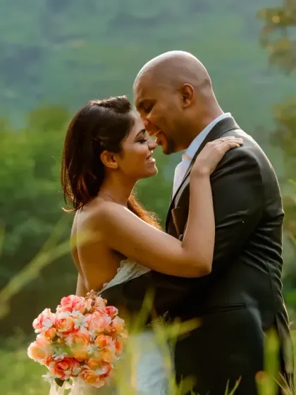 An intimate embrace surrounded by the soft, green hues of nature. The warm sunlight filters through the grass, creating a dreamy and romantic atmosphere for this close-up portrait.