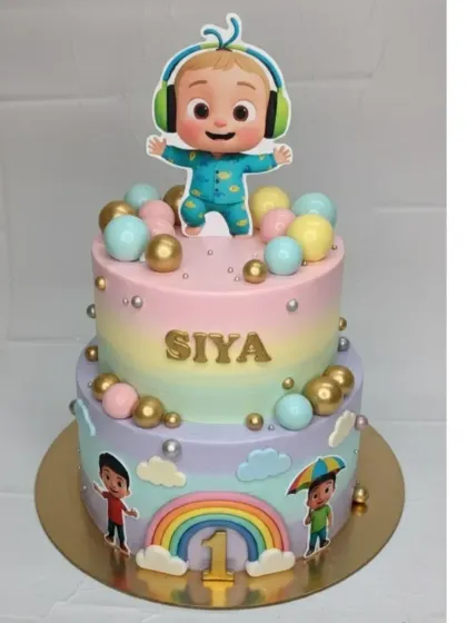 A vibrant two-tier Cocomelon cake for a first birthday. This mixed fruit cake features a pastel rainbow design and characters from the popular show.