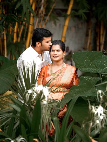 A romantic kiss on the forehead amidst a lush, green garden. This outdoor maternity shot feels intimate and secluded, perfectly capturing the couple's bond.