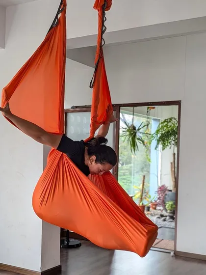 Cocooned in the safety of the orange hammock, this student experiences a moment of deep release and introspection during an aerial session.