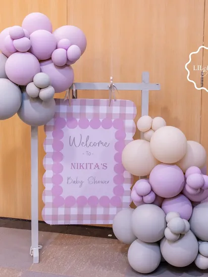 A charming welcome sign for Nikita's baby shower, featuring a gingham print and soft pastel balloon clusters to greet guests with style.