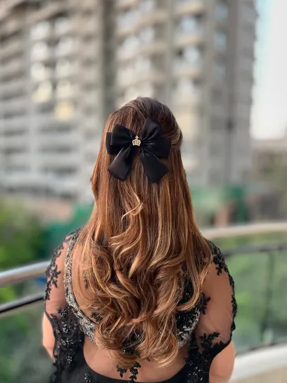 The back view of the half-up style, highlighting the black bow with a crown embellishment. I love using accessories to add a personalized and unique touch to my hairstyles.
