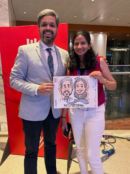 A couple poses with their caricature at a corporate gathering. It's a great ice-breaker and adds a fun, personal touch to professional events.