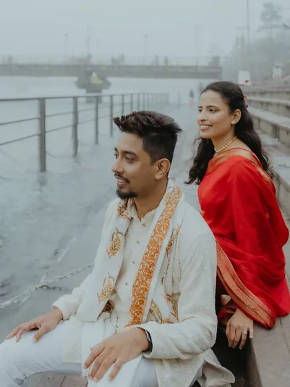 A candid shot of the couple sitting by the steps of the Ganga in Haridwar, enjoying a quiet moment together.