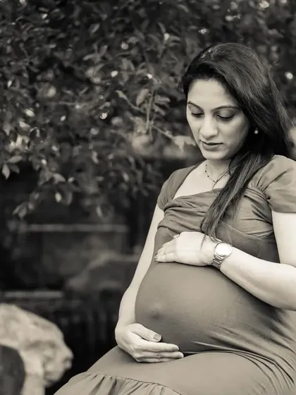 A contemplative and serene black and white portrait of a mom-to-be, looking down at her bump. It's a quiet, beautiful, and emotional image.