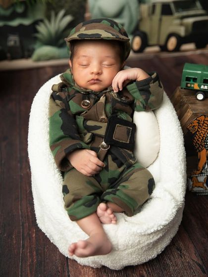 A close-up of the little army baby, showing the details of the camouflage outfit and cap.
