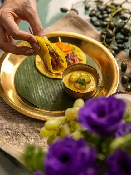 A guest enjoys a mini taco filled with savory goodness, paired with a creamy dipping sauce, from our fusion-inspired festive menu.