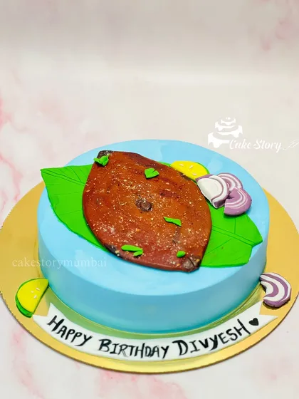 For the seafood lover, a Surmai Fry cake. I handcrafted an edible fried fish from fondant, complete with realistic coloring and texture, served on a banana leaf with lemon and onion.