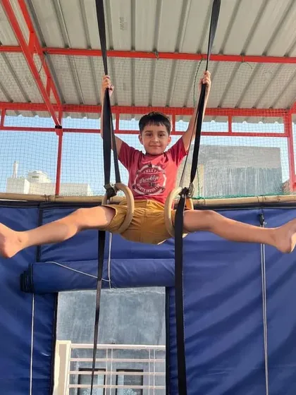 The joy of accomplishment. This young student is holding a challenging straddle pose on the rings.