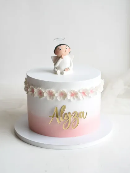 A sweet and simple cake for baby Alyza's baptism. This design features a pink ombre effect, a band of handmade sugar flowers, and an adorable angel topper.