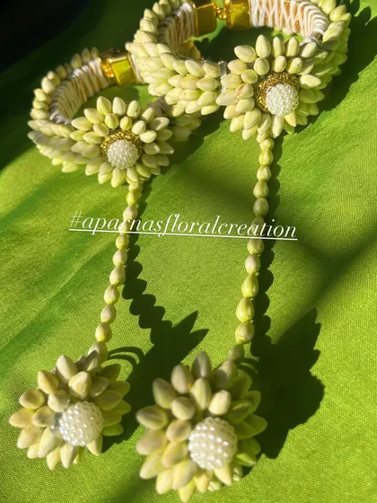 A pair of floral bangles or 'gajra' for the wrist. These are made from tightly woven flower buds and decorated with a floral motif and pearl center.