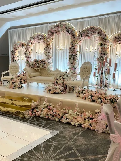 This reception stage is all about sophisticated glamour, featuring a series of grand floral arches in soft pink and white. The elevated platform, classic seating, and cascading flowers create a luxurious and picture-perfect setting for the newlyweds.