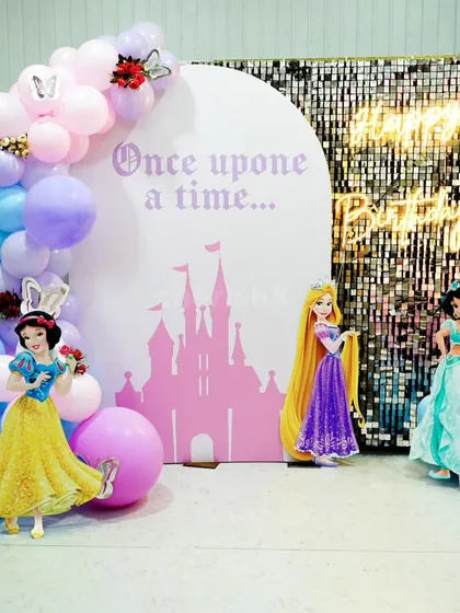 A "Once upon a time" princess theme with a sparkling sequin backdrop. The setup includes cutouts of Snow White, Rapunzel, and Jasmine.