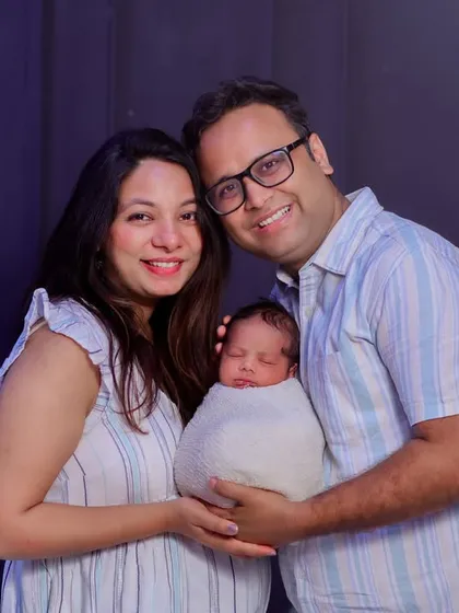 A bright and happy portrait of a new family. Their coordinated outfits and genuine smiles make this a joyful and classic image to remember this special time.