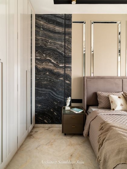 Where bold meets balanced, the striking black marble feature wall with organic veining becomes the focal point of this serene bedroom. Paired with soft beige paneling, mirrored insets, and a plush upholstered bed, the space exudes quiet luxury.
