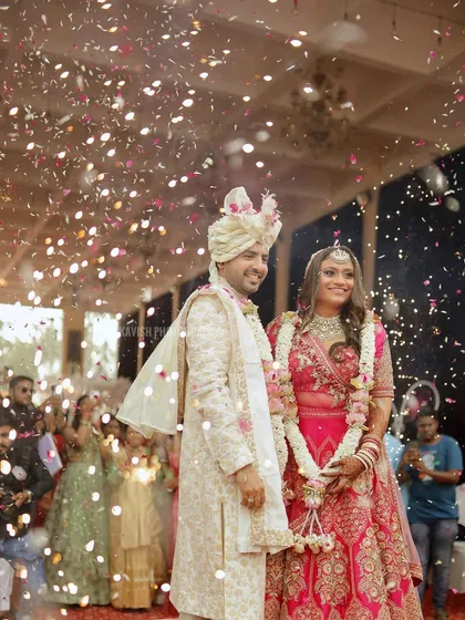 A candid wedding photograph capturing the bride and groom under a shower of confetti, a perfect moment of celebration.