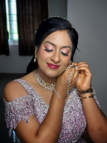 A candid moment of her adjusting her jewellery, her pink eyeshadow and bold lip standing out.