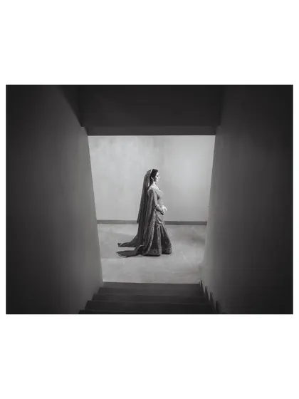 A minimalist and powerful black and white composition, using the stark architecture to frame the bride and create a sense of solitude and elegance.