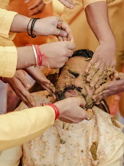 A candid shot of the groom being playfully covered in haldi by his friends.
