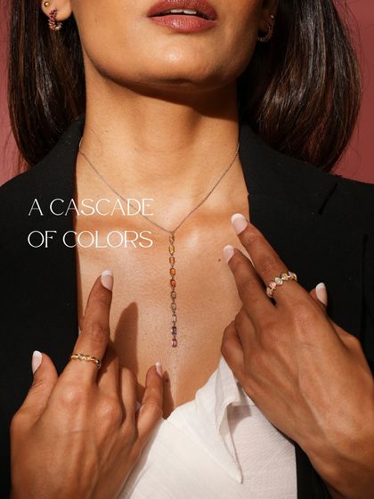 A cascade of colors. This image shows a model wearing the Rainbow Sapphire lariat necklace, a piece that reimagines a rainbow in sapphires and gold.