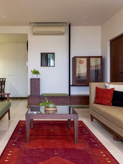 This living room in an Ahmedabad apartment balances comfort and style with two distinct sofas and a bold red rug. We used custom furniture and curated art to add personality, creating a space that feels collected and personal rather than formally decorated.