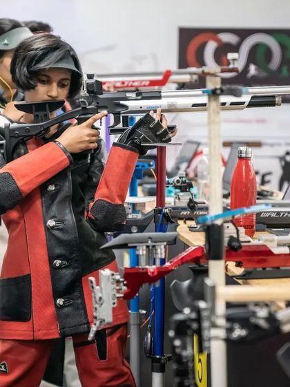 Two of our rifle shooters in their specialized gear, practicing their standing positions. The electronic targets in the background provide immediate performance data.