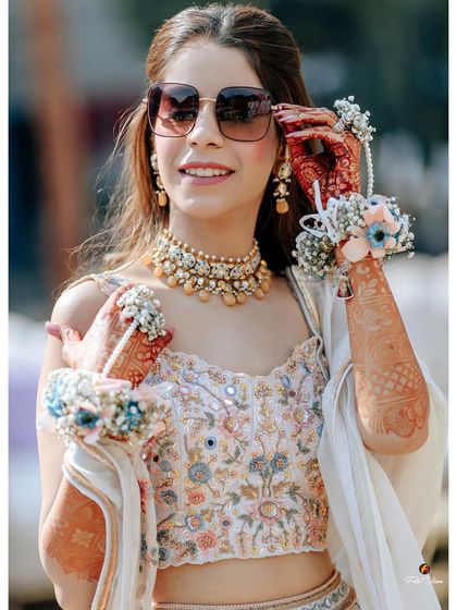 A close-up of the bride from her Mehendi, highlighting her floral jewelry and stylish sunglasses.