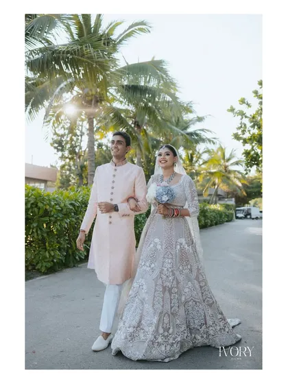 The couple takes a romantic stroll under the palm trees at their Thailand beach wedding venue, a perfect picture of destination bliss.