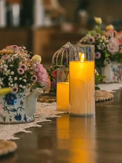 A detail of the English tea party baby shower tablescape, with vintage-style teapots used as flower vases and warm pillar candles creating a cozy atmosphere.