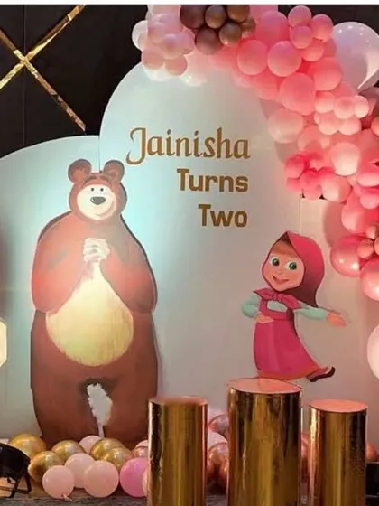 A 'Masha and the Bear' themed second birthday party with character cutouts and a pink balloon arch.
