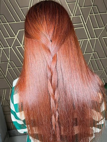 A beautiful example of a rich, warm red global color. The simple braid highlights the shine and single-tone finish of the hair.