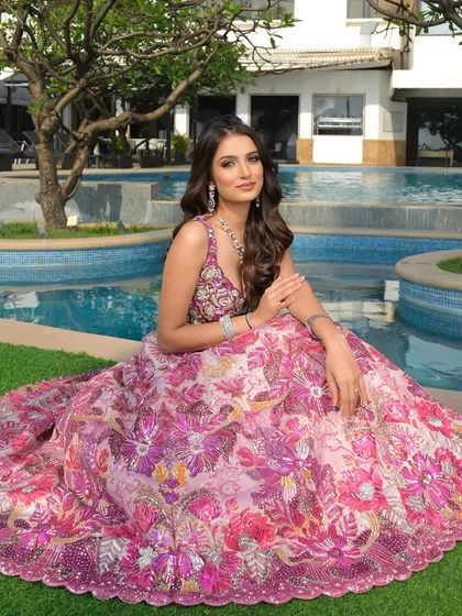A princess moment by the pool. This shot showcases the full, magnificent floral skirt of the lehenga, with her soft glam makeup and hair providing the perfect finishing touch.