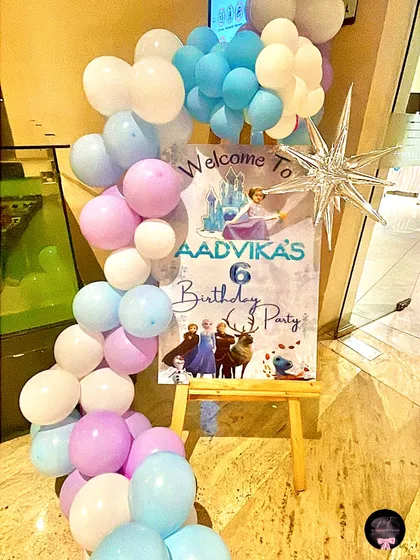 A closer look at the personalized welcome sign for Aadvika's 6th birthday party, framed by a beautiful cascade of 'Frozen' themed balloons.